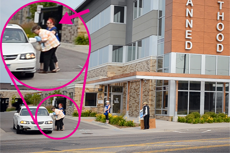 PP escort in blue vest tries to interfere with a sidewalk counselor in St. Paul, Minn.