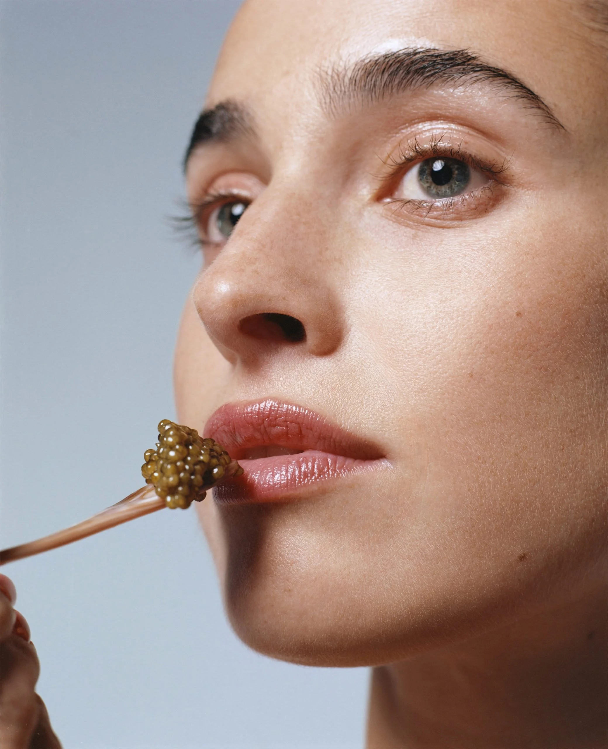 Nahaufnahme eines Mädchens, das an einem Pinsel mit Kaviar leckt.