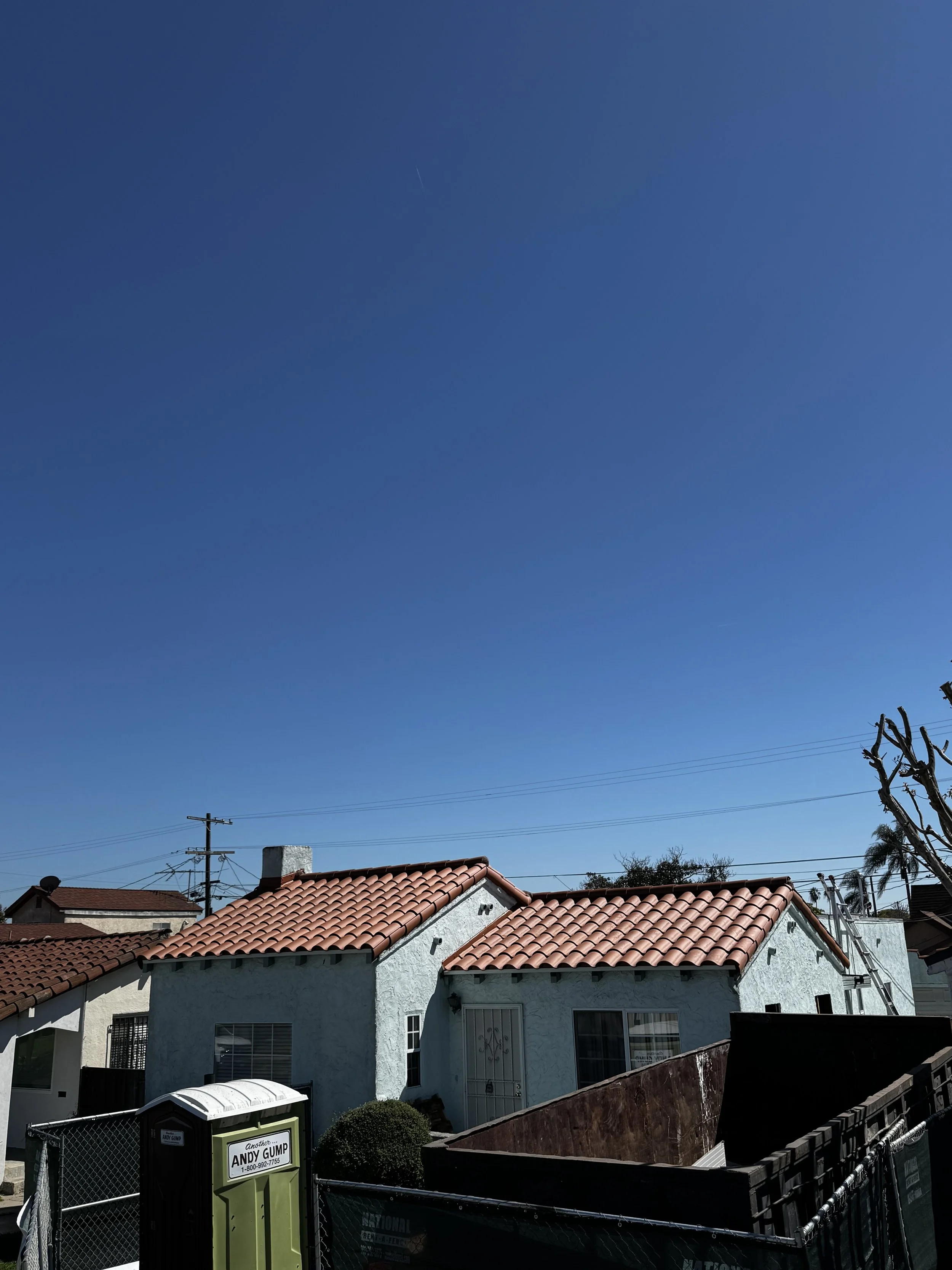 A neighborhood scene with houses featuring red tile roofs and a bright blue sky.
