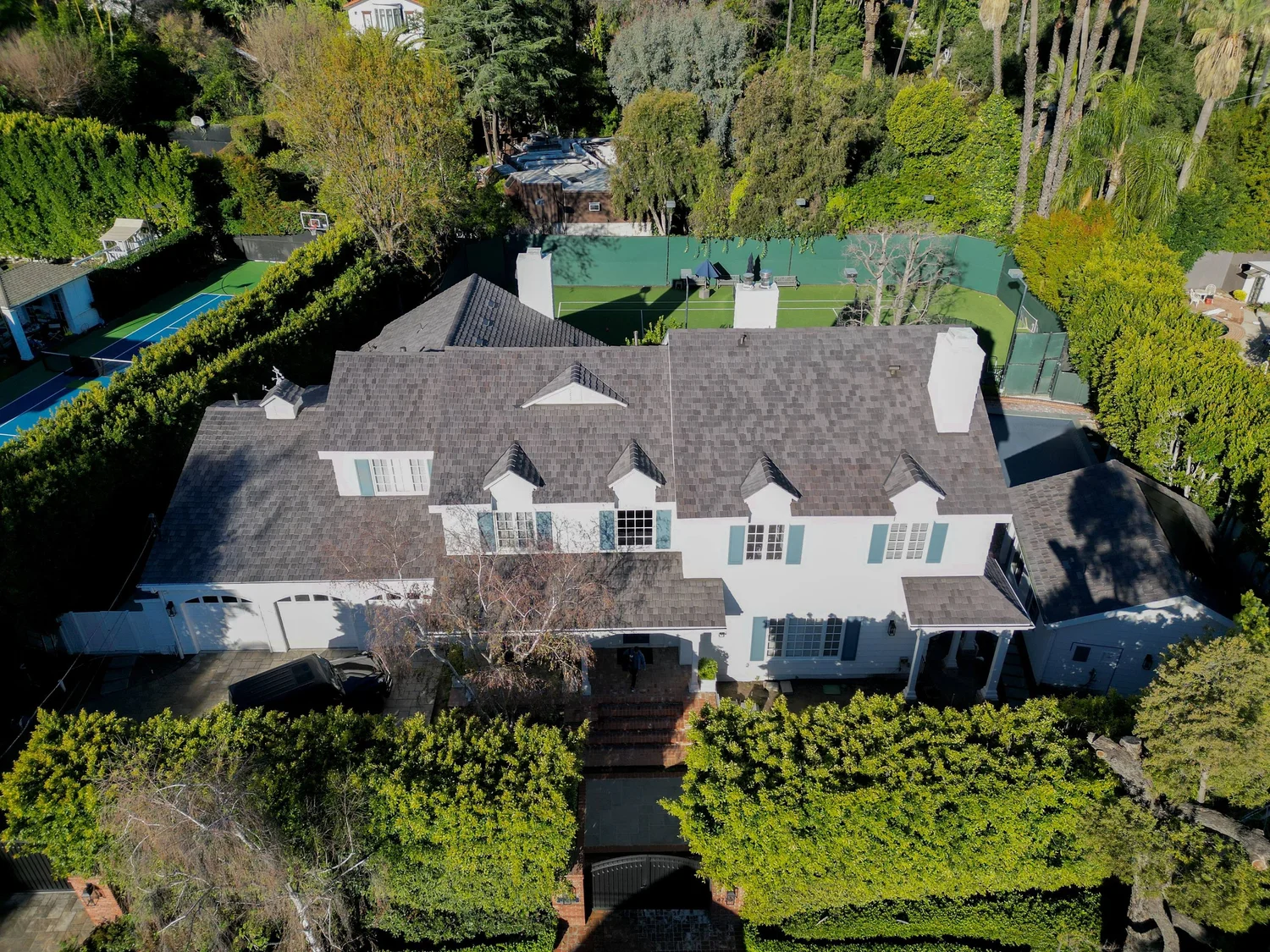 Aerial view of a home with a gray roof surrounded by trees