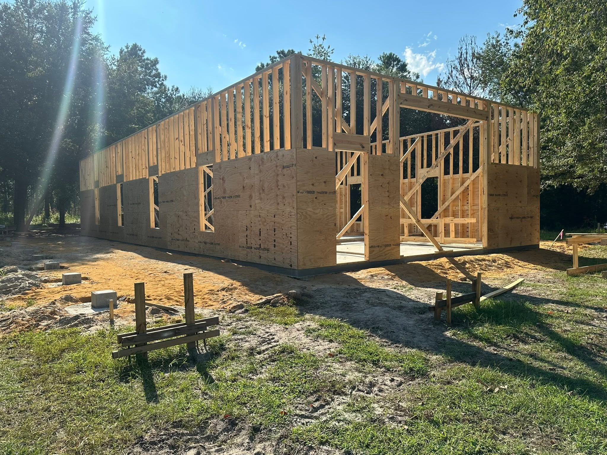 Wooden framing of a house under construction in a wooded area during daytime.