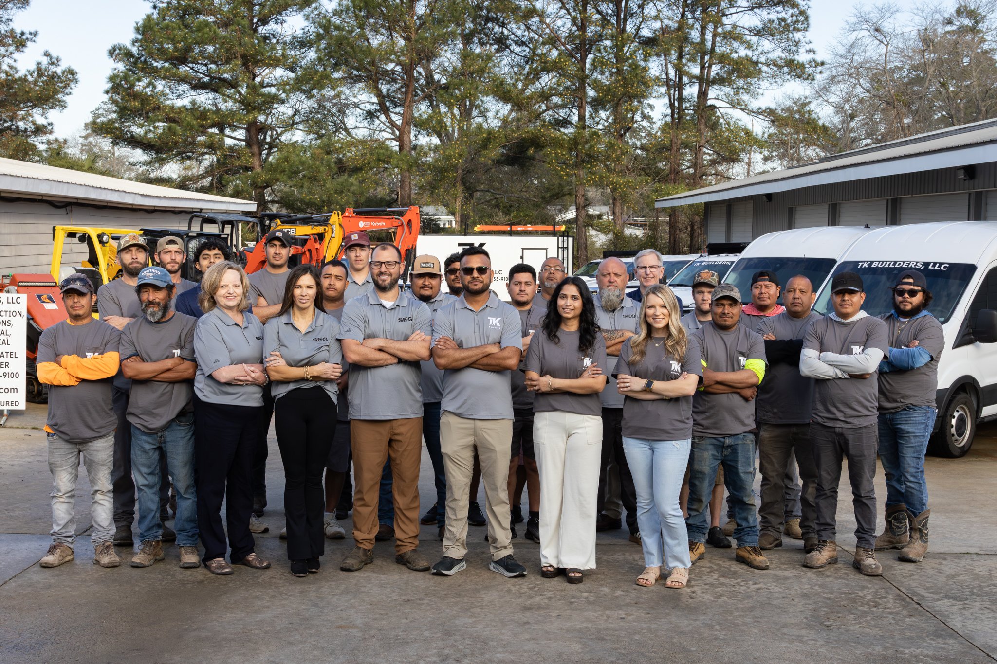 TK Builders crew wearing company shirts at an outdoor construction site.