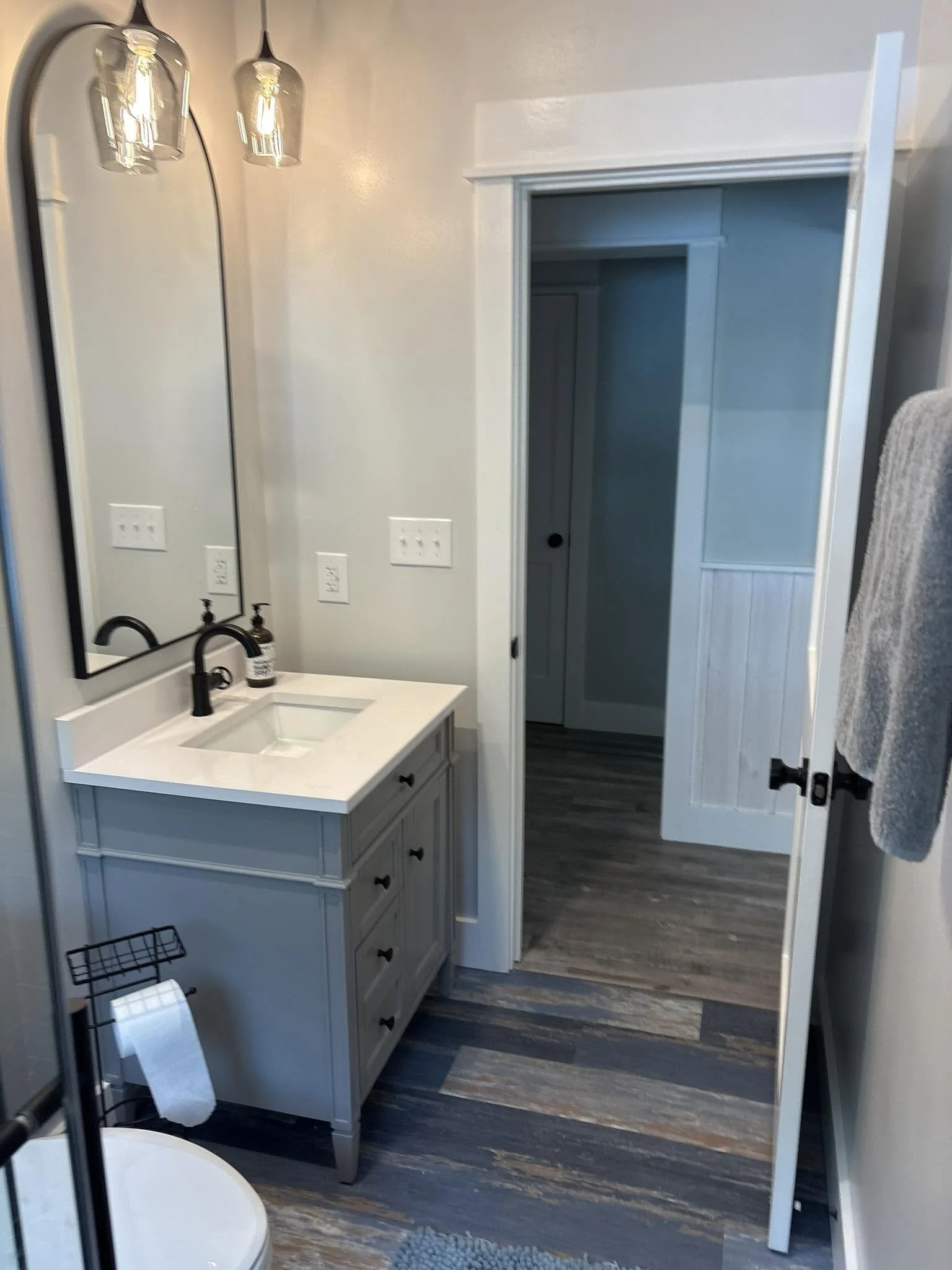 A bathroom with a white vanity, a mirror, two wall-mounted light fixtures, a faucet, and a closet door.