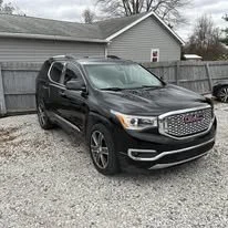 Black SUV parked on a gravel driveway in front of a house with a wooden fence.