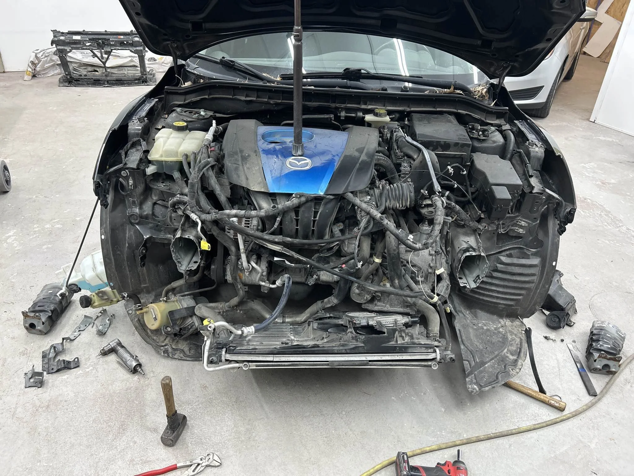 View of a disassembled car engine with various parts and tools around it in a garage.