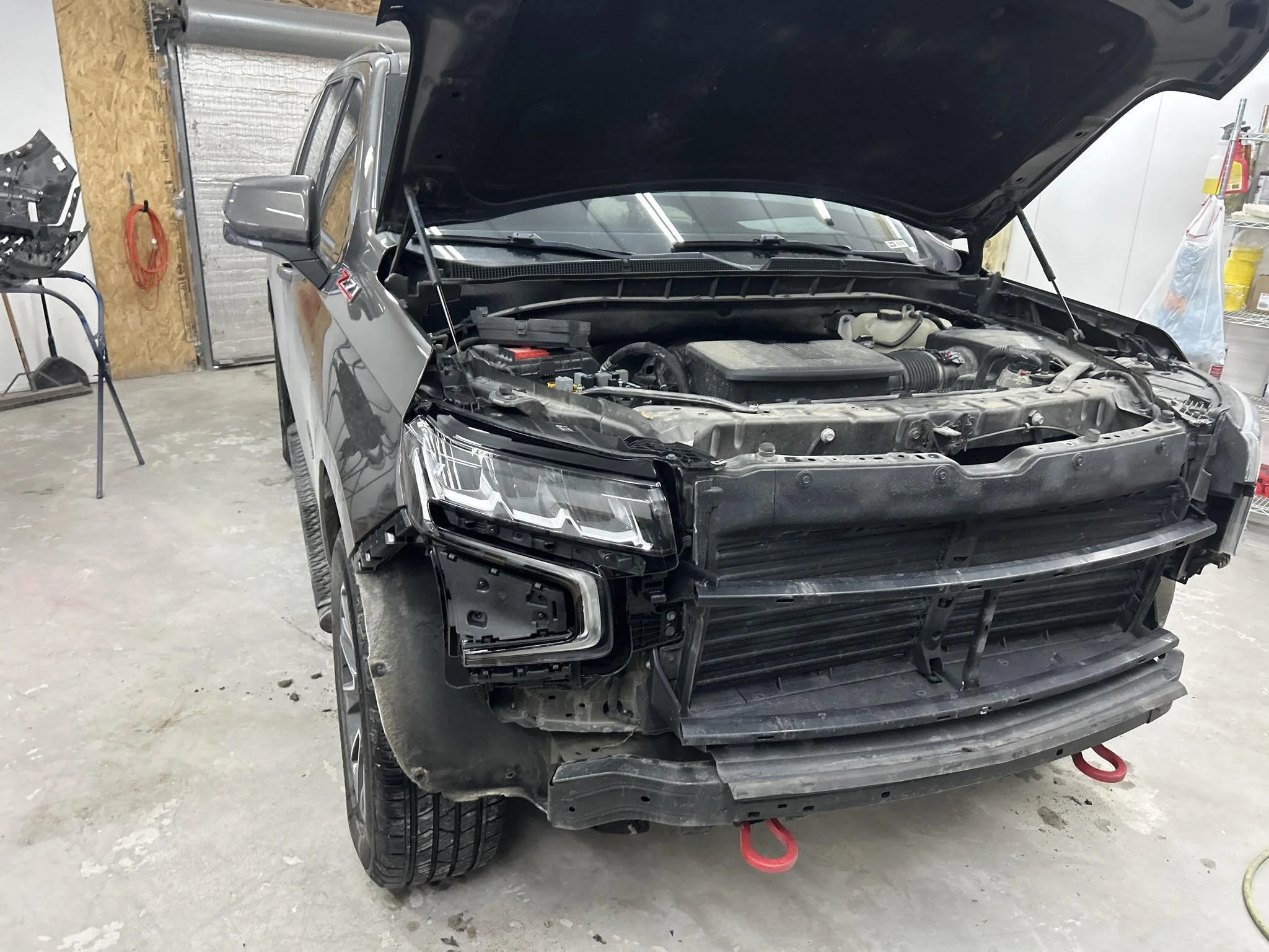 A black pickup truck with an open hood in a garage or workshop, showing the engine and engine bay.