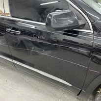 Close-up of the black car's side door showing a noticeable dent and scratch.