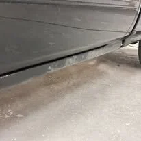 Close-up of a car's undercarriage and the dusty ground beneath it