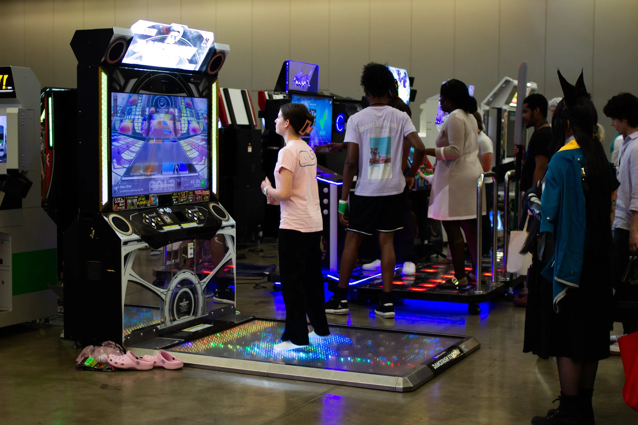 People playing dance arcade game in an indoor arcade or entertainment center.