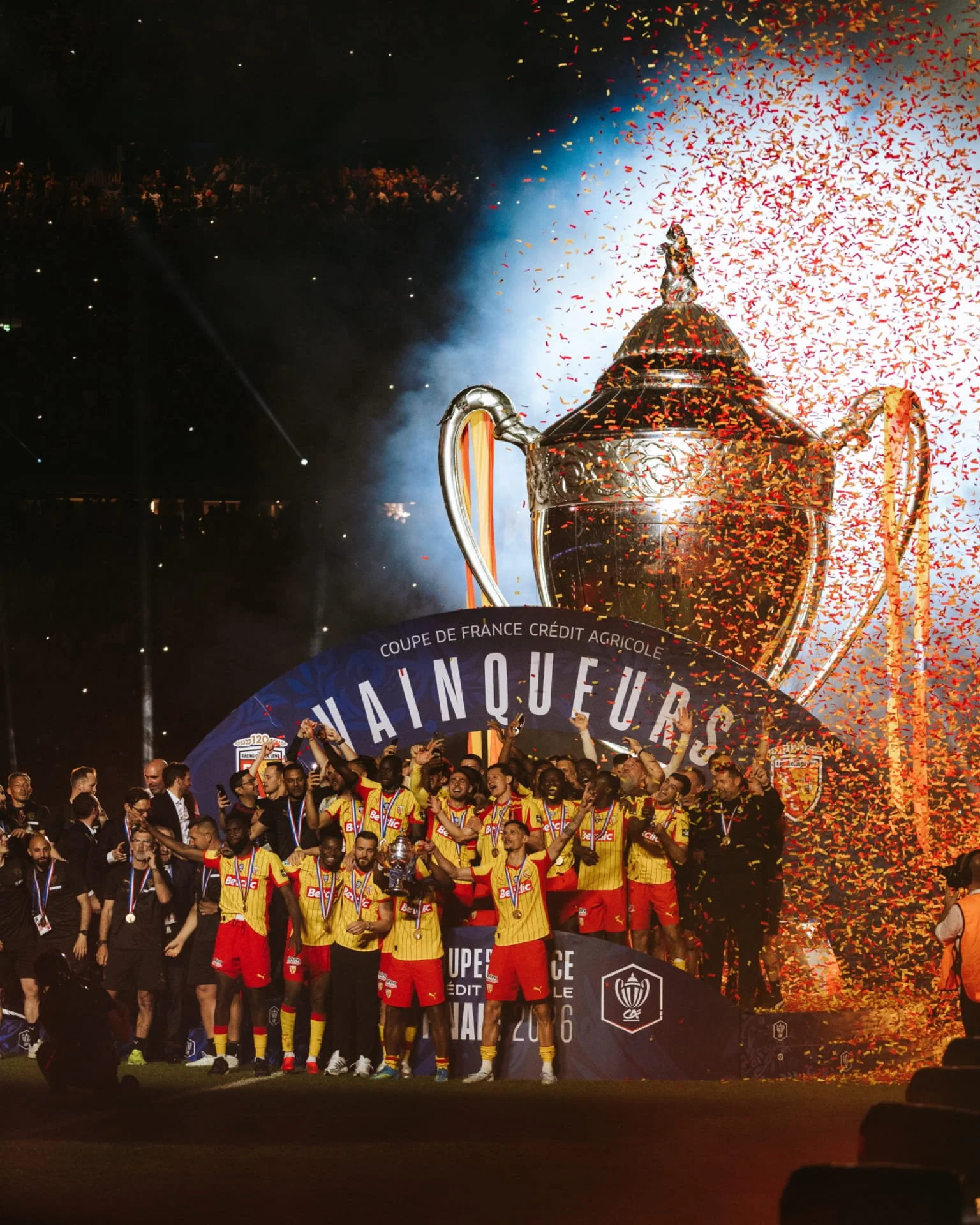 Cauê Foto, photographe de mariage , portrait et événementiel. Une équipe de football célèbre victorieusement avec un trophée, sous un feu d'artifice et des confettis, en 2026, lors d'une célébration de la coupe de France remportée par Lens.