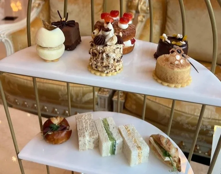 Raffles The Palm Blüthner Hall afternoon tea cakes and sandwiches a three tiered marble and gold stand.