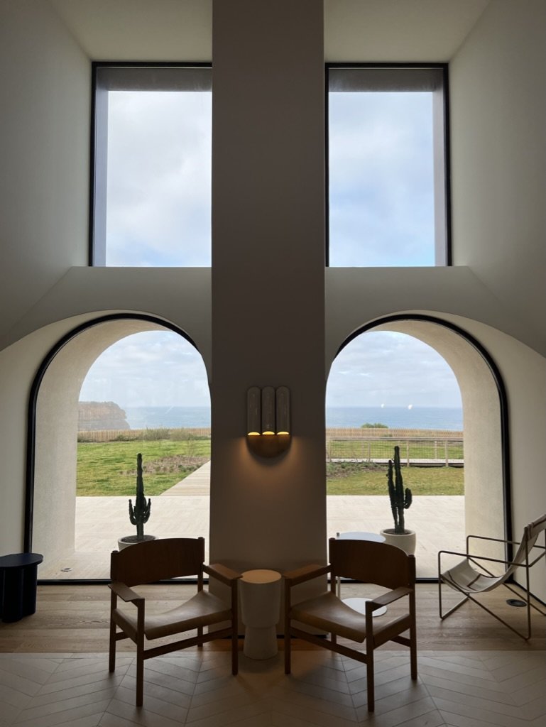 Ocean view from Aethos Ericeira. Two chairs in the windows with a cactus in the centre of each.
