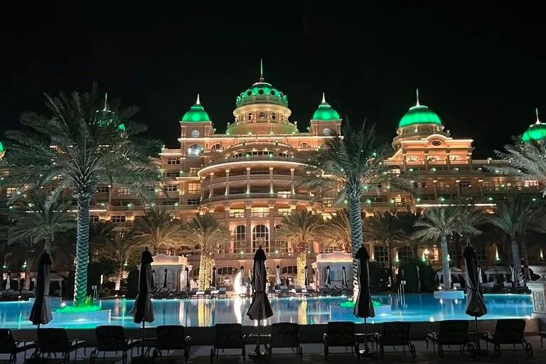 Raffles The Palm pool and illuminated hotel view at night.