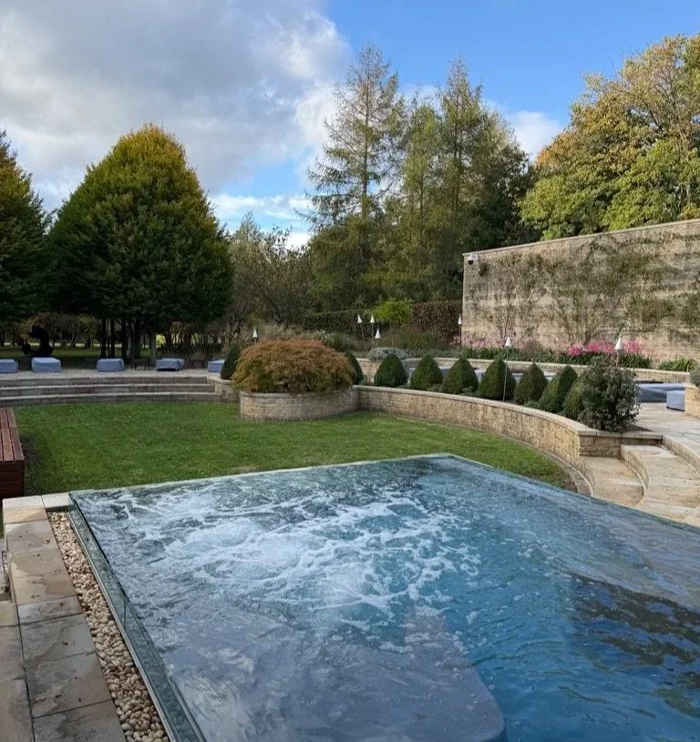 The hydrotherapy pool outside with bubbles and the garden and trees behind.