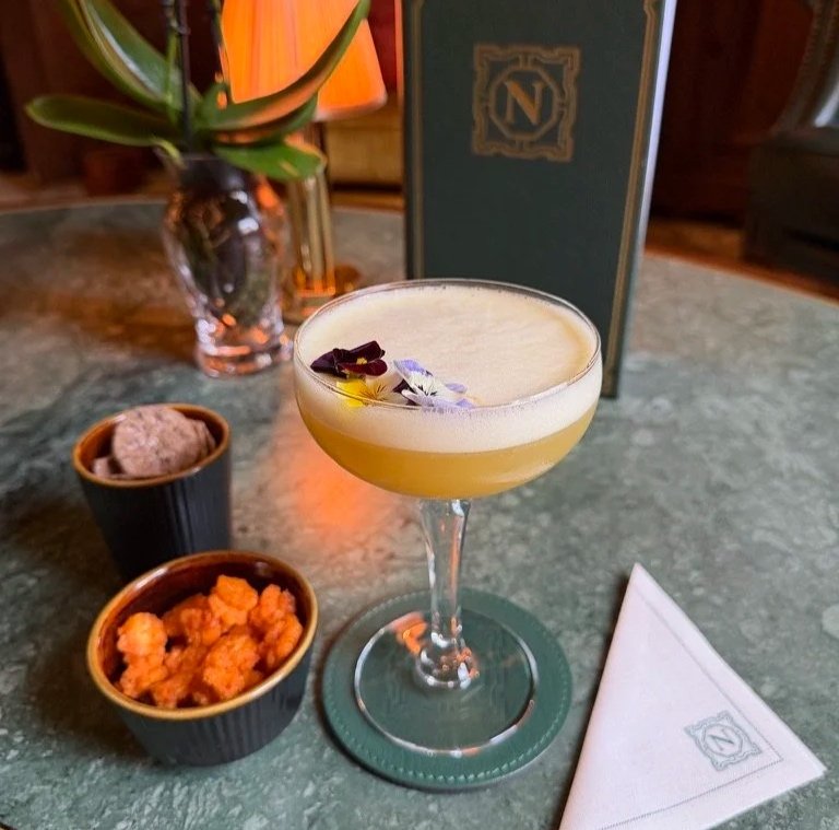 Yellow creamy mocktail in Norton Bar at Grantley Hall with spicy snacks and pepper crackers.