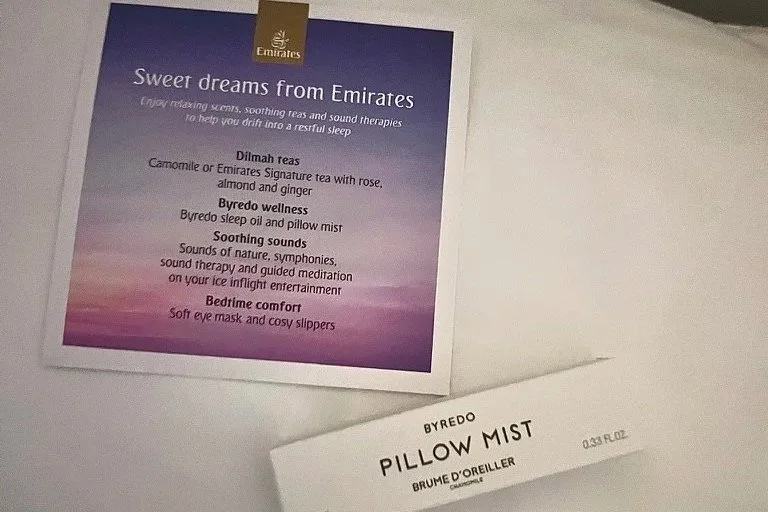 Emirates first-class sleep mist and sweet dreams card on white pillow in dark lighting.