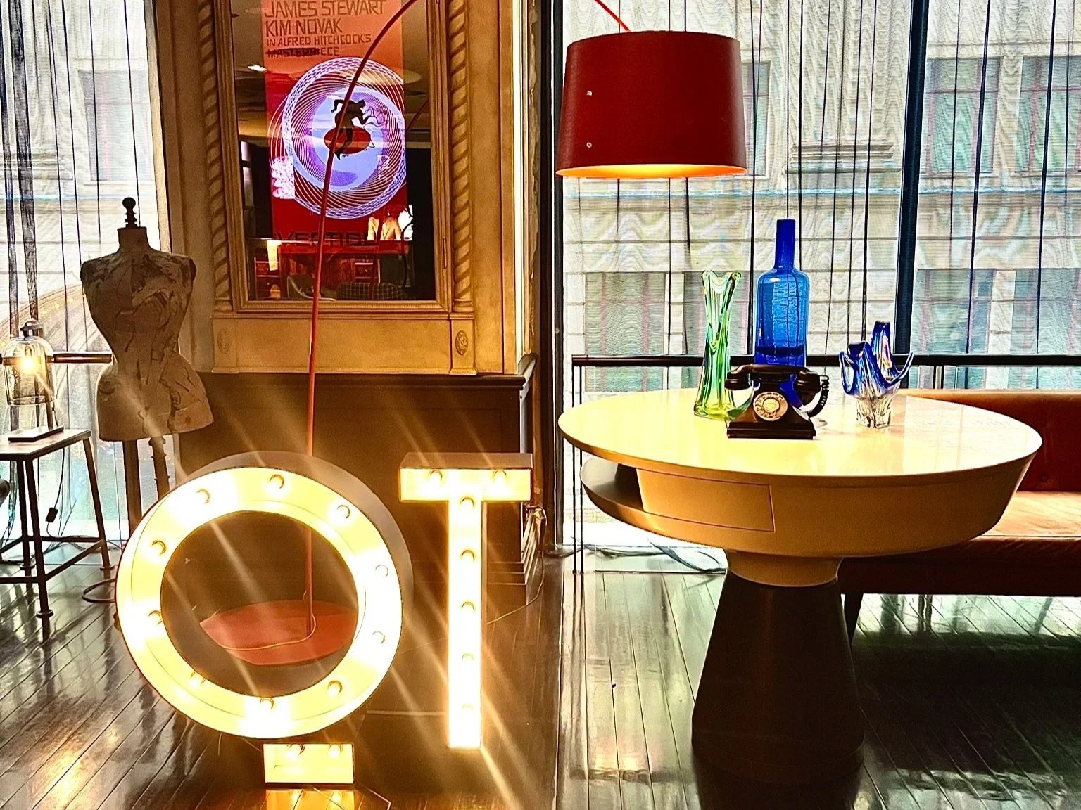 Sydney QT illuminated signage with quirky artefacts to the right on a round table.