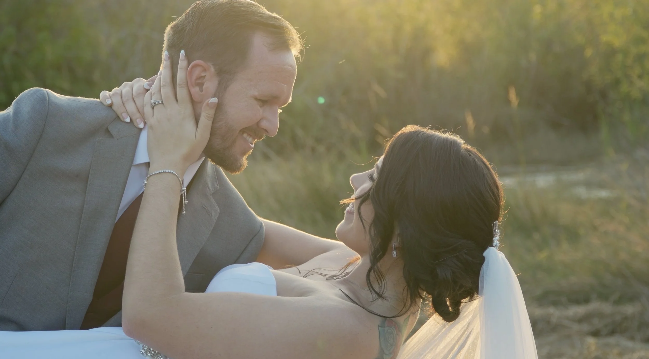 A man and woman sharing a romantic moment outdoors at sunset, smiling and looking into each other's eyes.