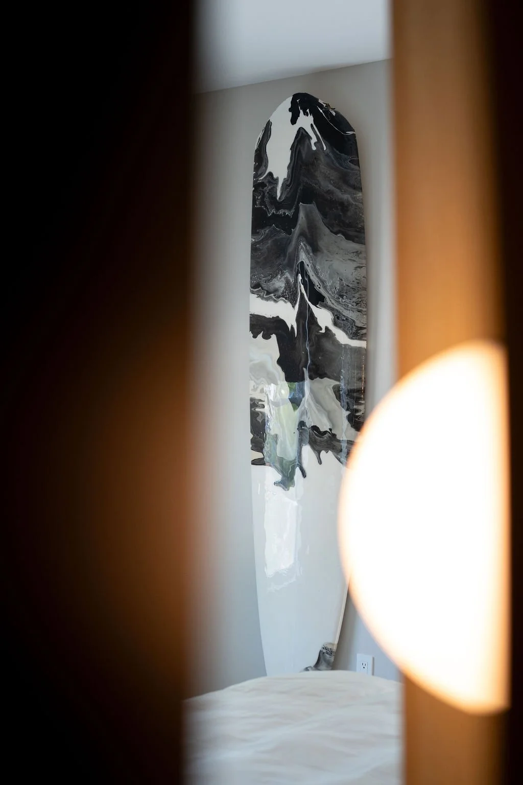 A room viewed through a partially opened door with a black and white abstract art piece on the wall.