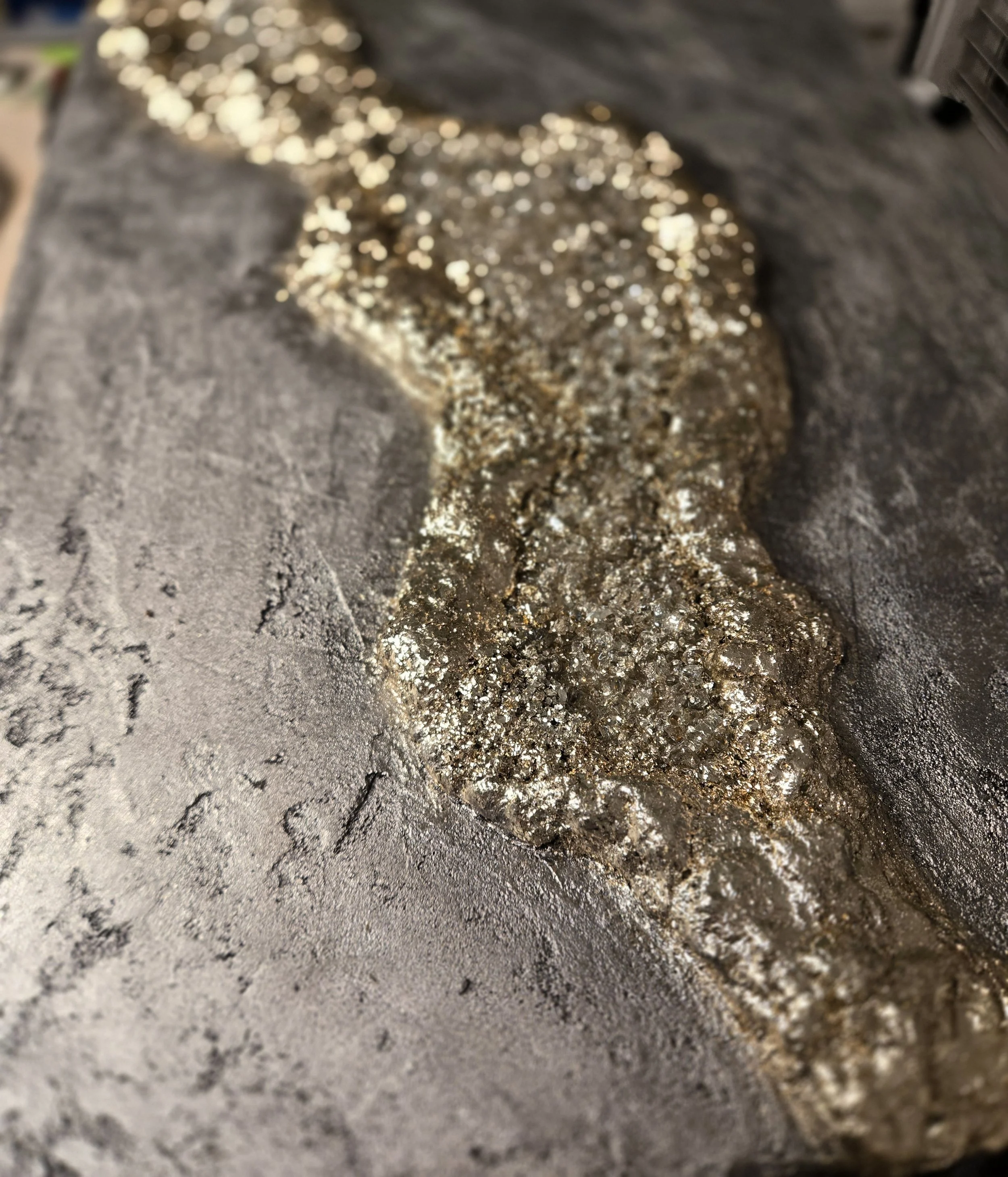 Close-up of a metallic or mineral substance with shiny, sparkly particles on a rough surface.