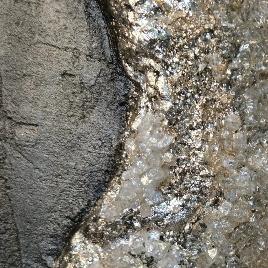 Close-up of a rough textured surface with water and small stones or gravel.