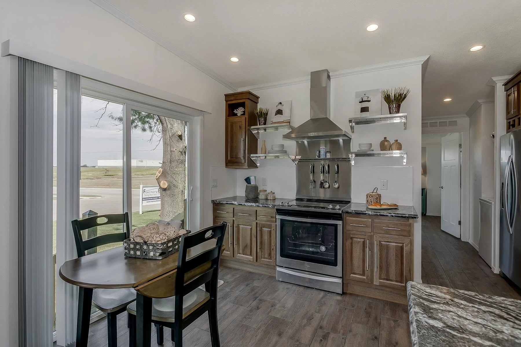 Kitchen with sliding glass door, eating table, and kitchen appliances, decorative items, and open shelving.