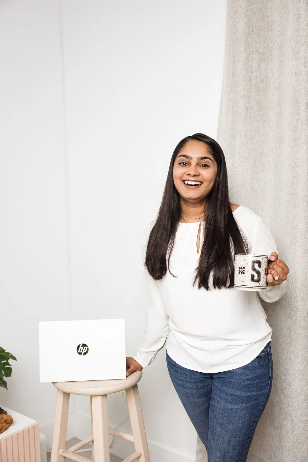 Shivani Solanki Patel holding a coffee mug beside her laptop