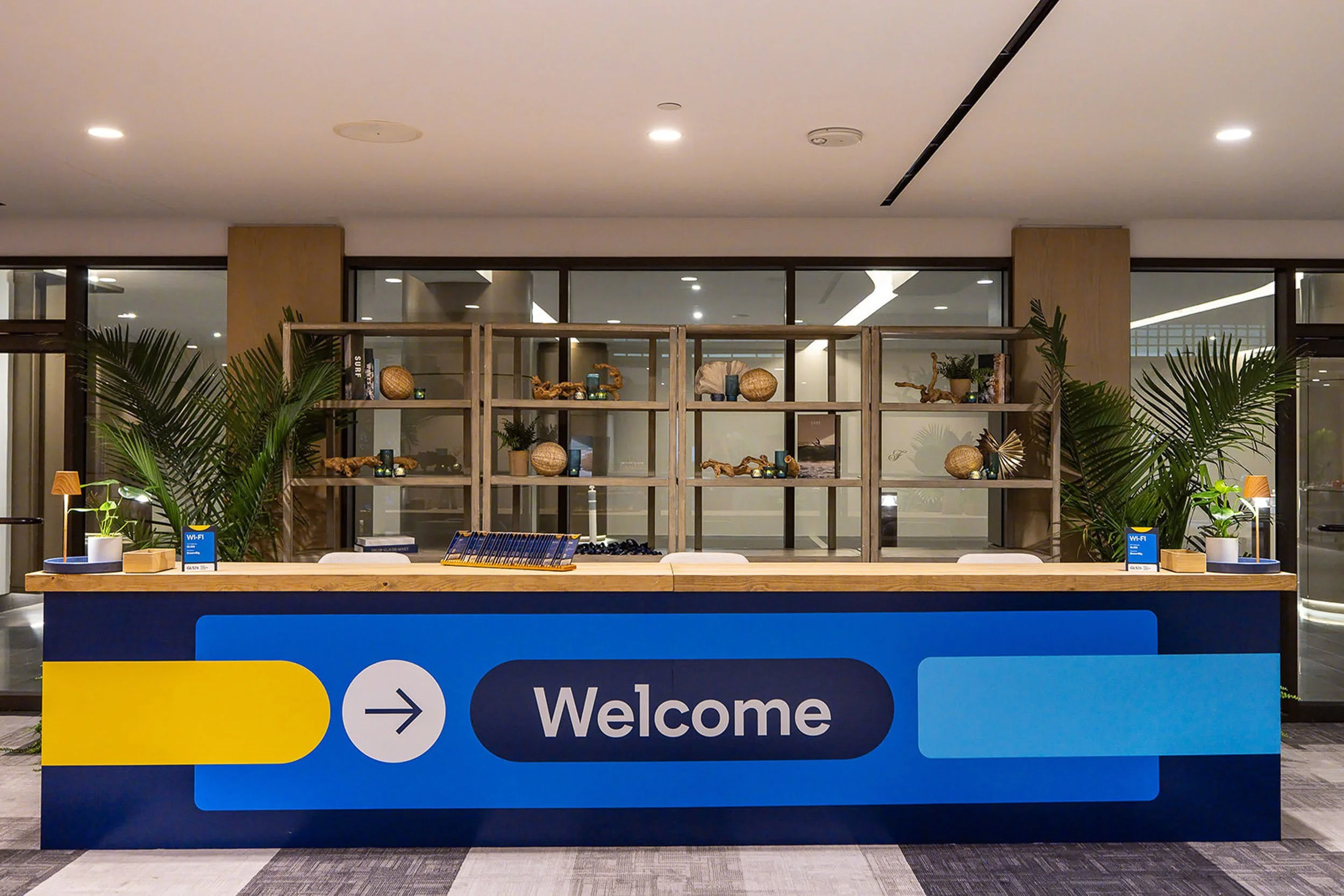 Walmart welcome desk inside the store with decorative shelves, green plants, and a sign indicating Wi-Fi availability.