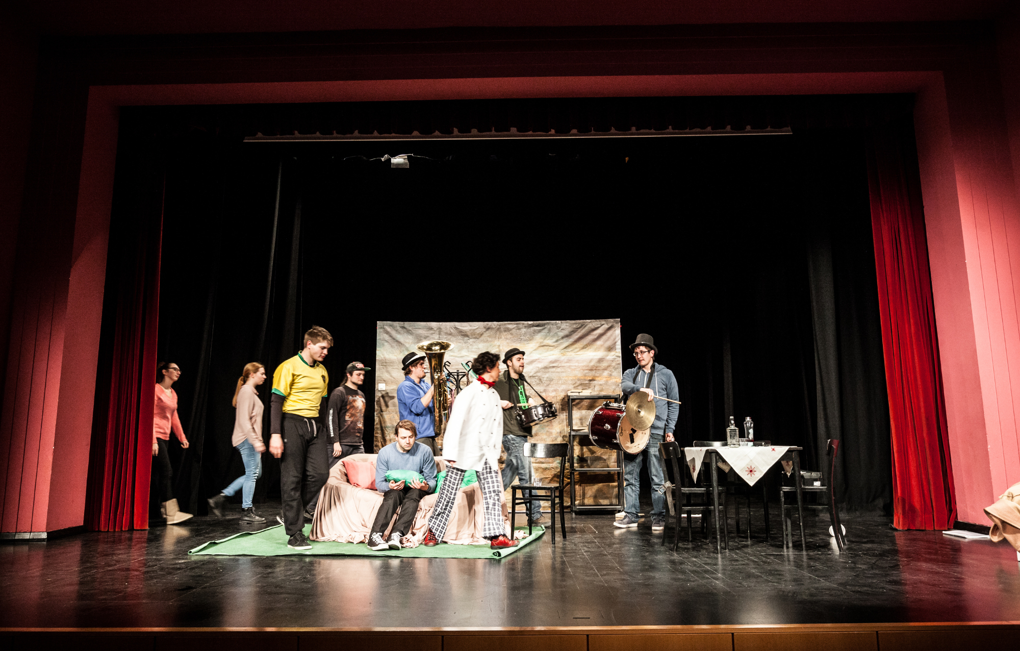 Group of performers on stage during a theatrical rehearsal or play, with various costumes and props.