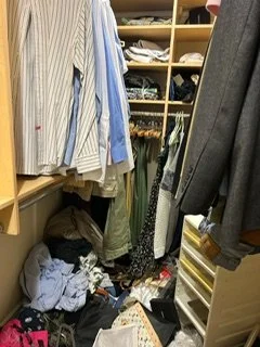 Clothing and shoes cluttered on the floor in a walk-in closet with open shelving and hanging clothes