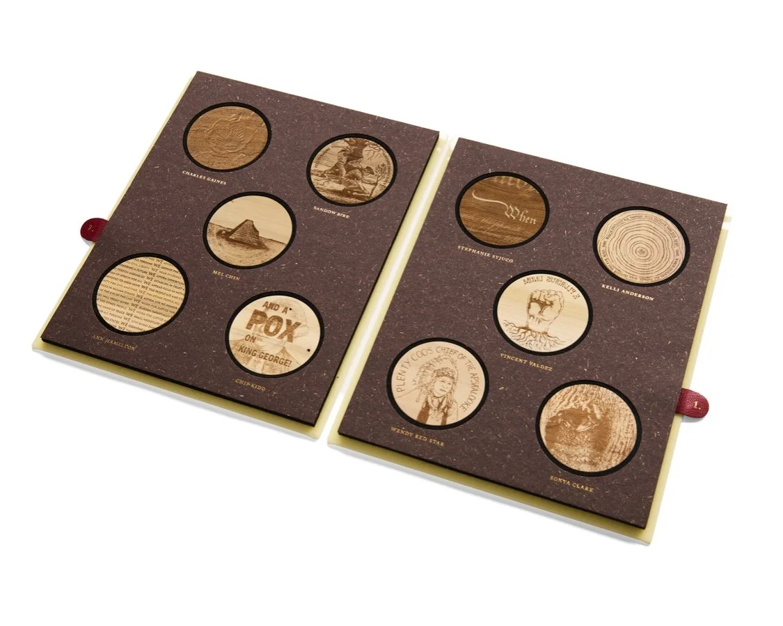 Open book displaying circular images, each with a different design or text, on a brown background with red ribbon bookmarks.