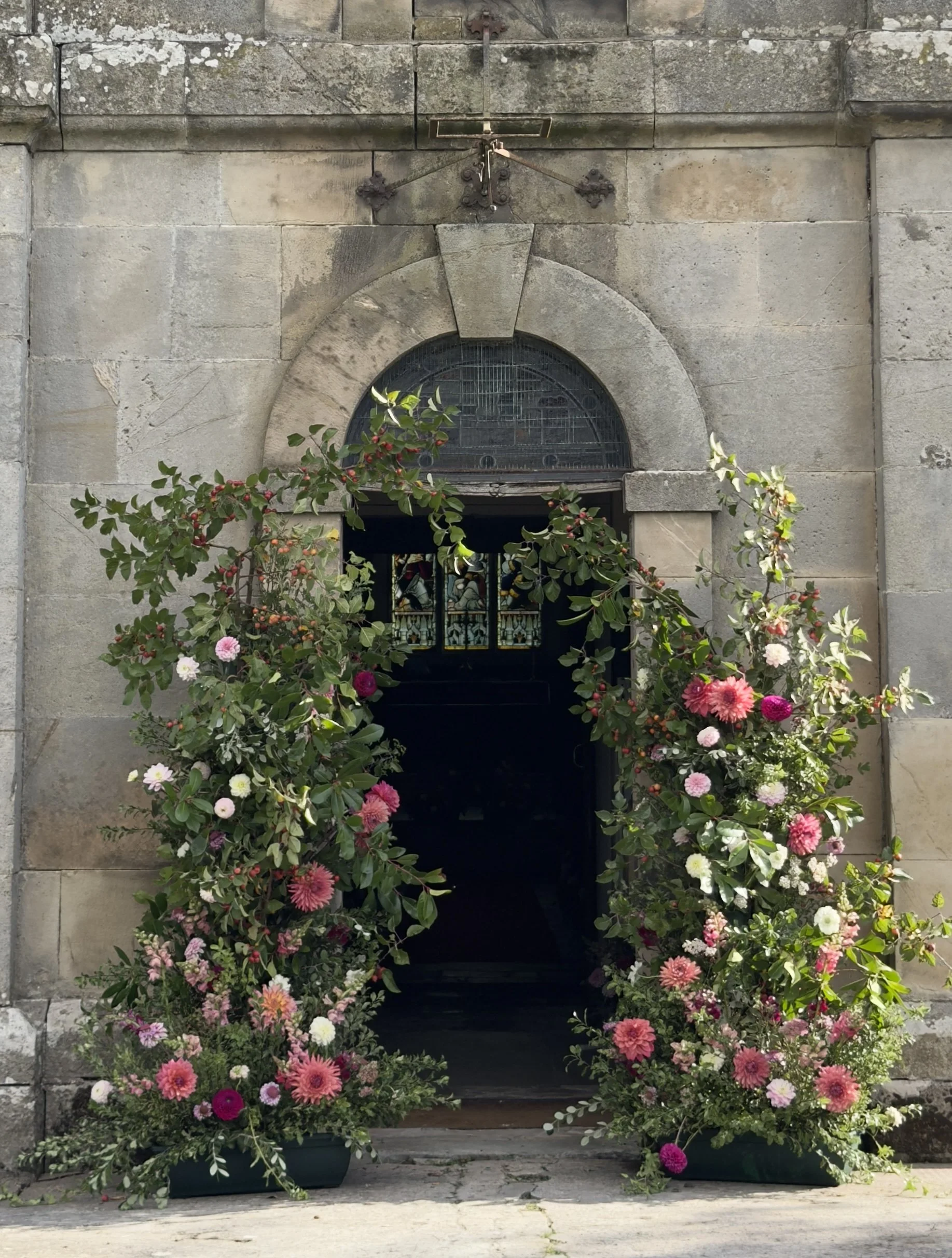 A floral wedding arch outside a church