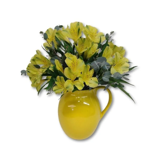 Yellow pitcher filled with a bouquet of yellow flowers and green foliage.