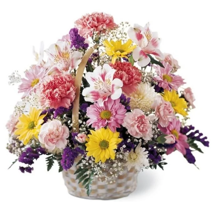 A basket filled with a variety of pink, yellow, purple, and white flowers, including daisies and carnations.