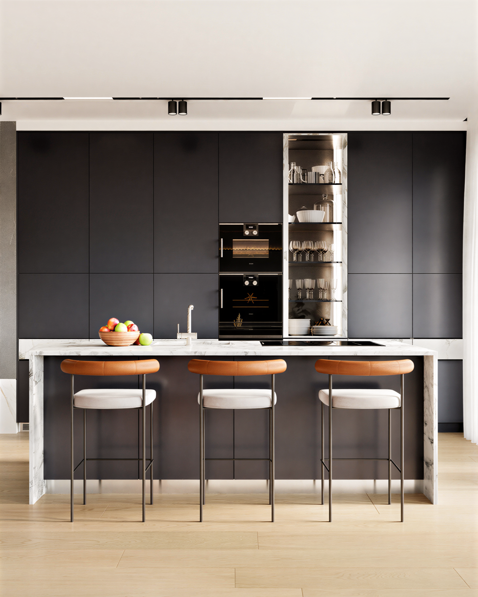 Modern kitchen with black cabinetry, marble island with three bar stools, built-in oven, open shelving with glassware and a bowl of fruit.