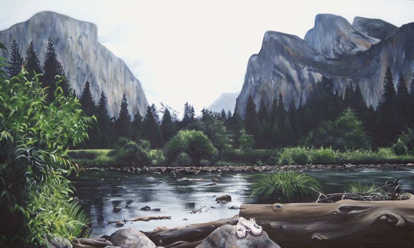 A painting of a river set in a forested valley with mountains in the background, and a pair of hiking shoes on a log in the foreground.