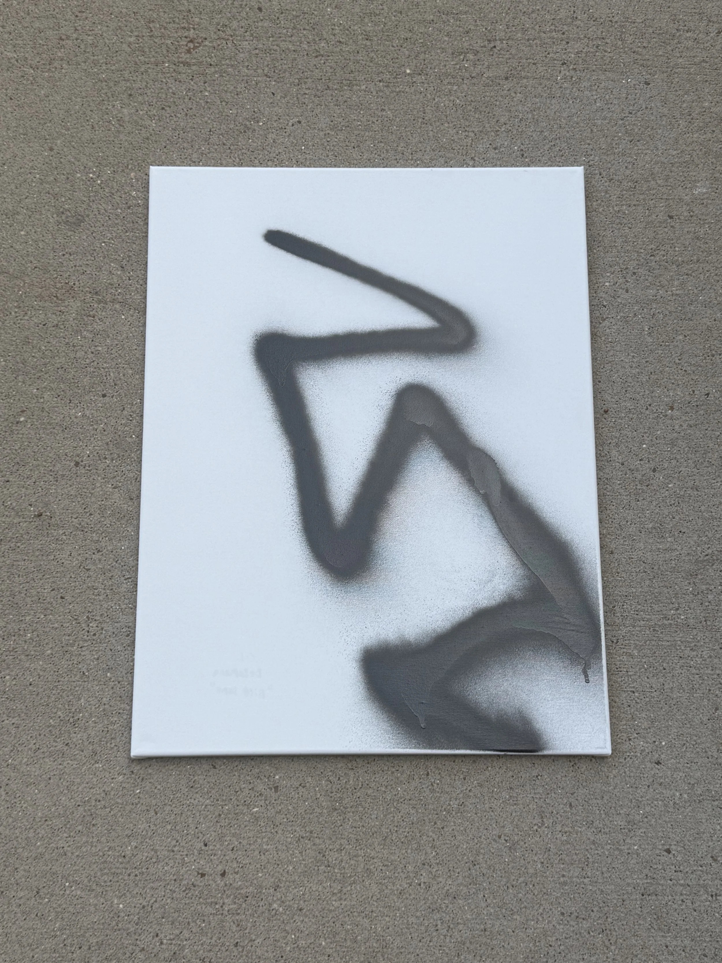 A white canvas with black spray paint graffiti forming a stylized abstract shape.