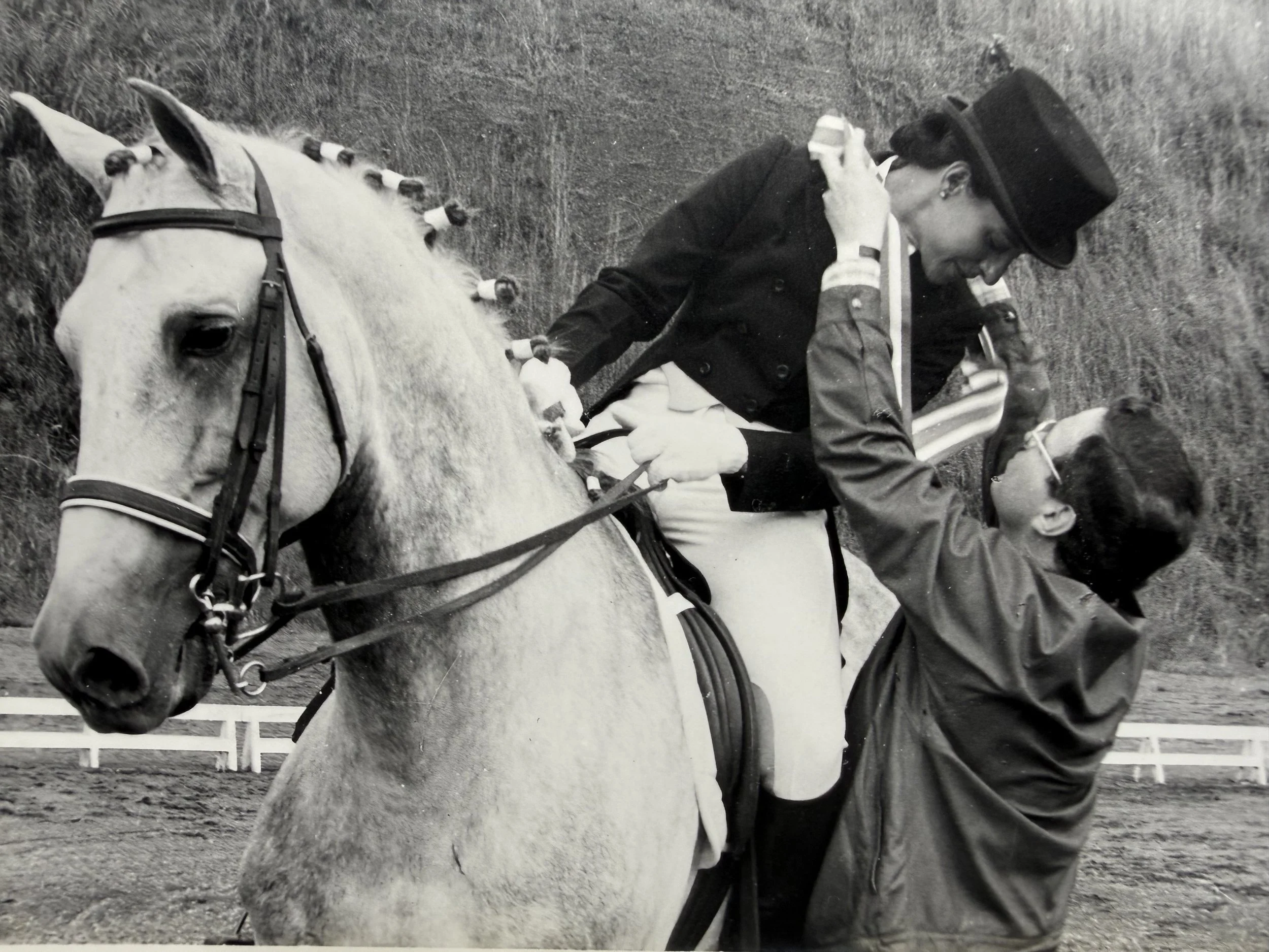 Una mujer montando a caballo en un corral de equitación.