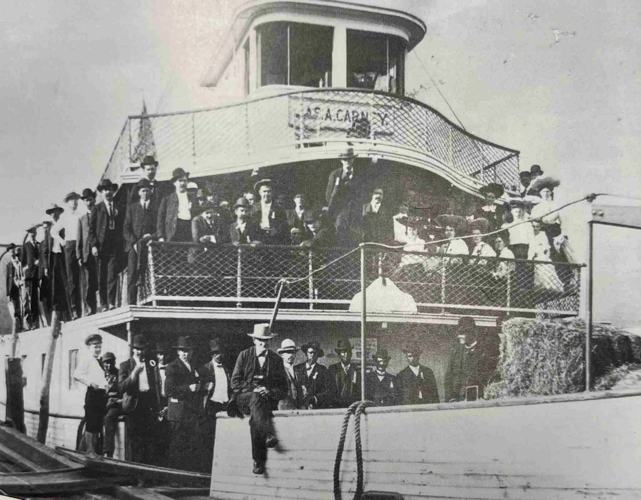 Black and white photo of a group of men and women gathered on a boat