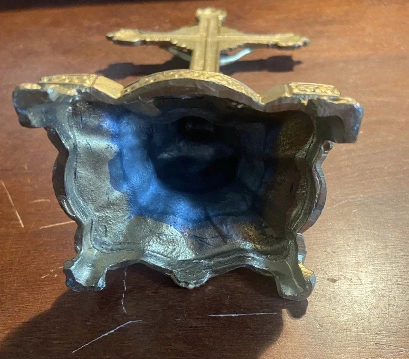 A close-up of a metallic object resembling a seashell with an opening, and an airplane model on top, placed on a wooden surface.