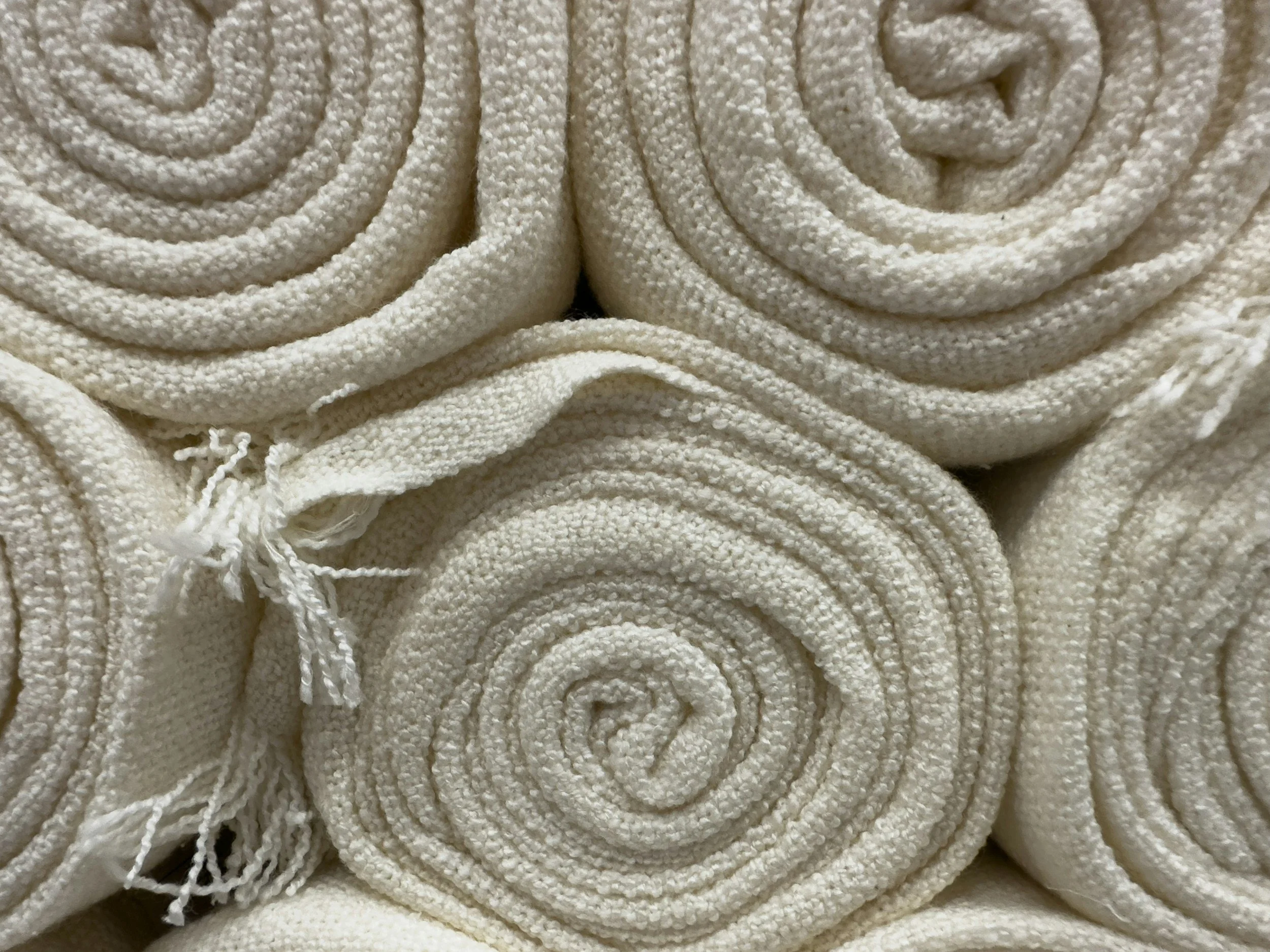 Close-up of rolled white towels stacked together.