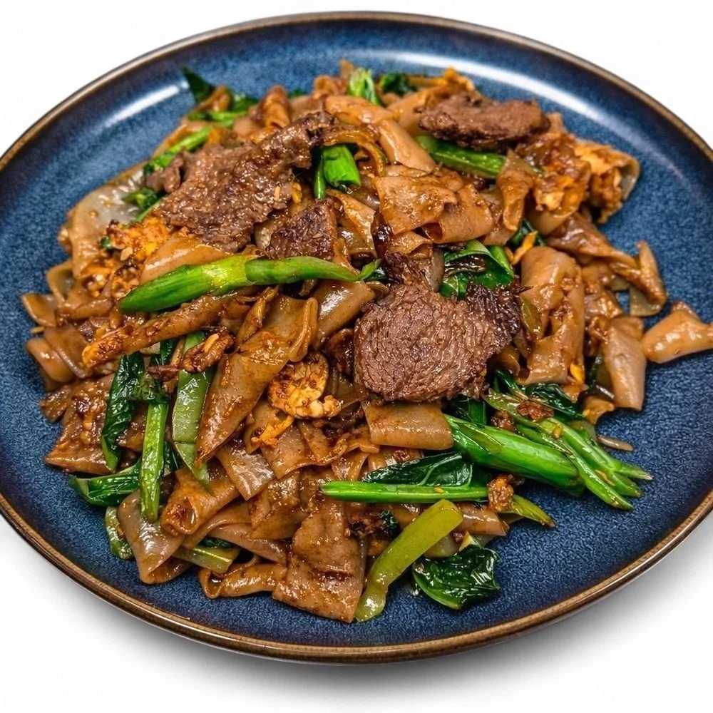 Plate of stir-fried beef, noodles, green onions, and vegetables on a blue plate.