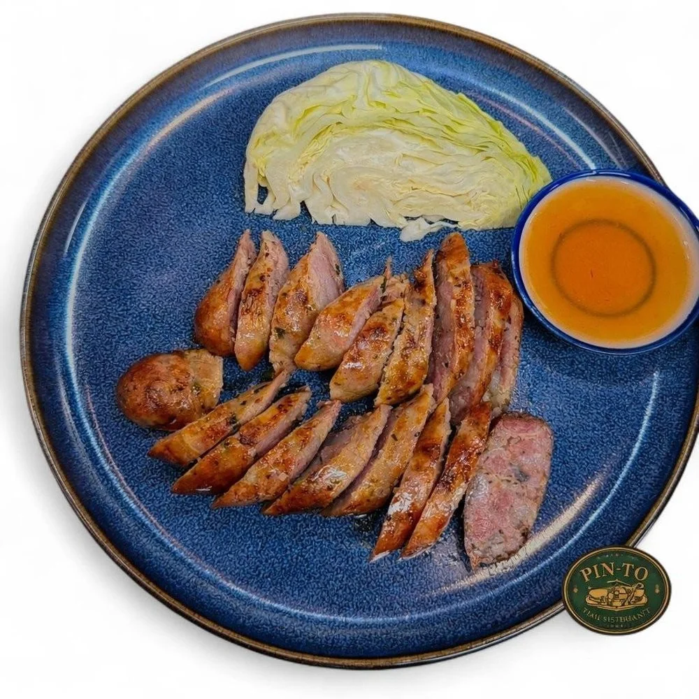 Plate of sliced grilled meat, a small bowl of dipping sauce, and a wedge of cabbage on a blue plate.