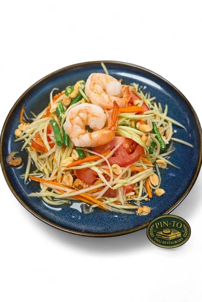 Seafood salad with shrimp, vegetables, and peanuts on a blue plate.