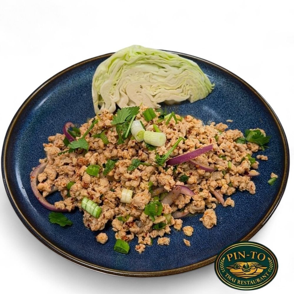 Plate of Thai chicken minced meat salad with chopped green onions, red onion slices, cilantro, and a side of cabbage on a blue plate with Pin To Thai Restaurant logo.