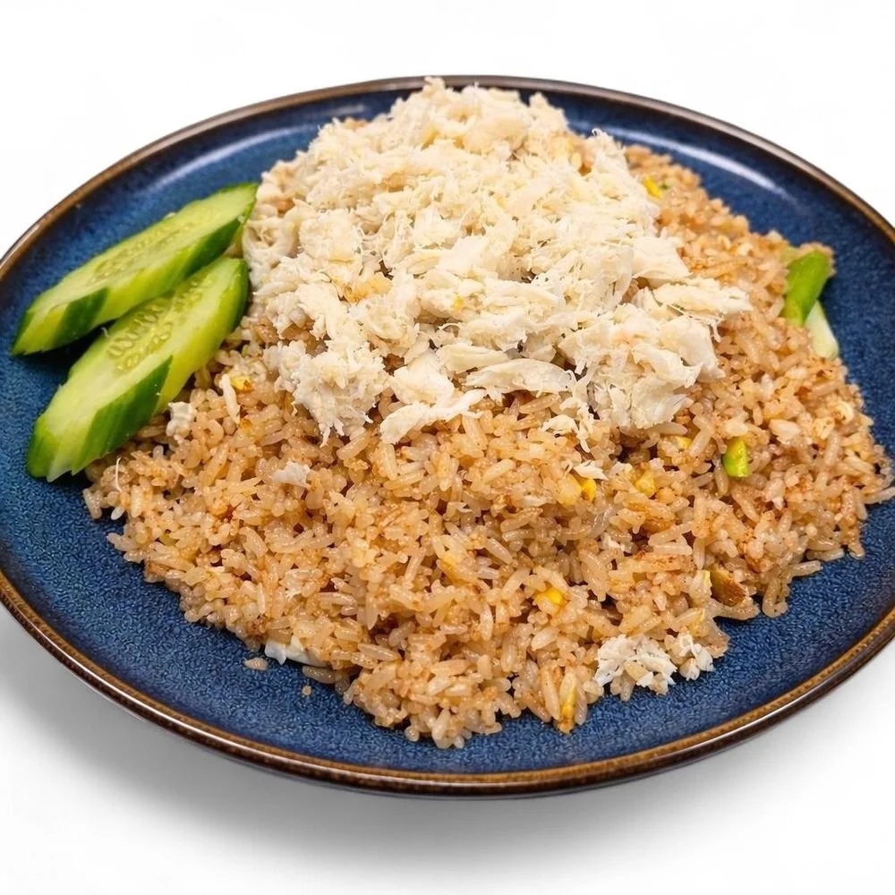 Plate of fried rice topped with shredded chicken and sliced cucumbers on a blue dish.