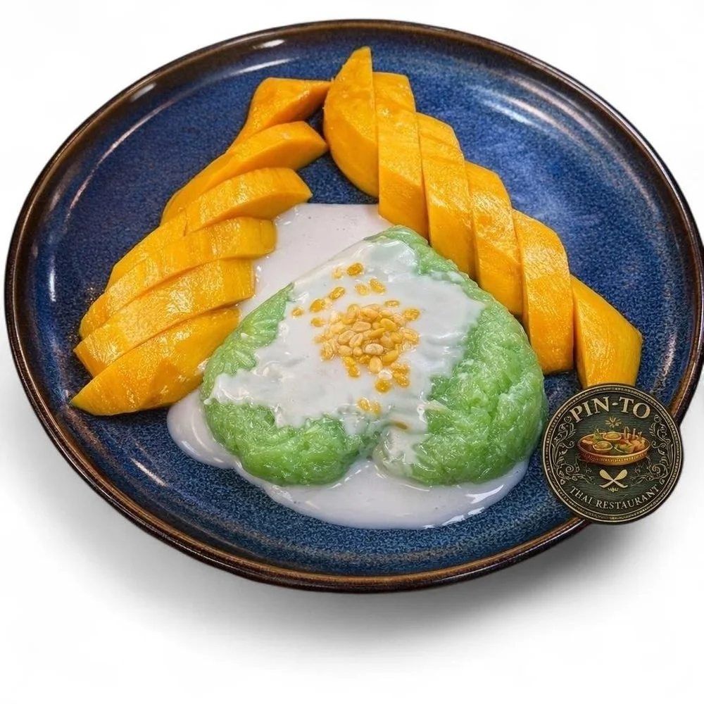 Sliced mango, a scoop of green sticky rice with coconut milk and crushed peanuts on a blue ceramic plate.