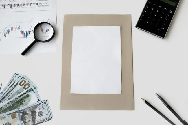 desk top view with paper money, calculator, pens, representing ways to track monthly spending