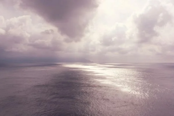 horizon over open body of water with rain clouds and sun shining through representing how much you should save for retirement