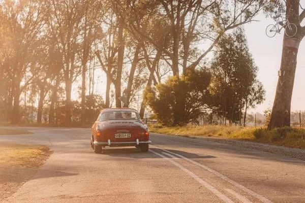 red small sports car driving down a country road depicting leasing vs. buying a car